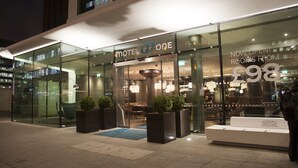 A modern hotel entrance with a glass facade, a sign reading "Motel One," and a price tag of £98. - Motel One London-Tower Hill (London)