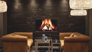 A cozy living room with a fireplace, leather sofas, and a TV. - Motel One London-Tower Hill (London)