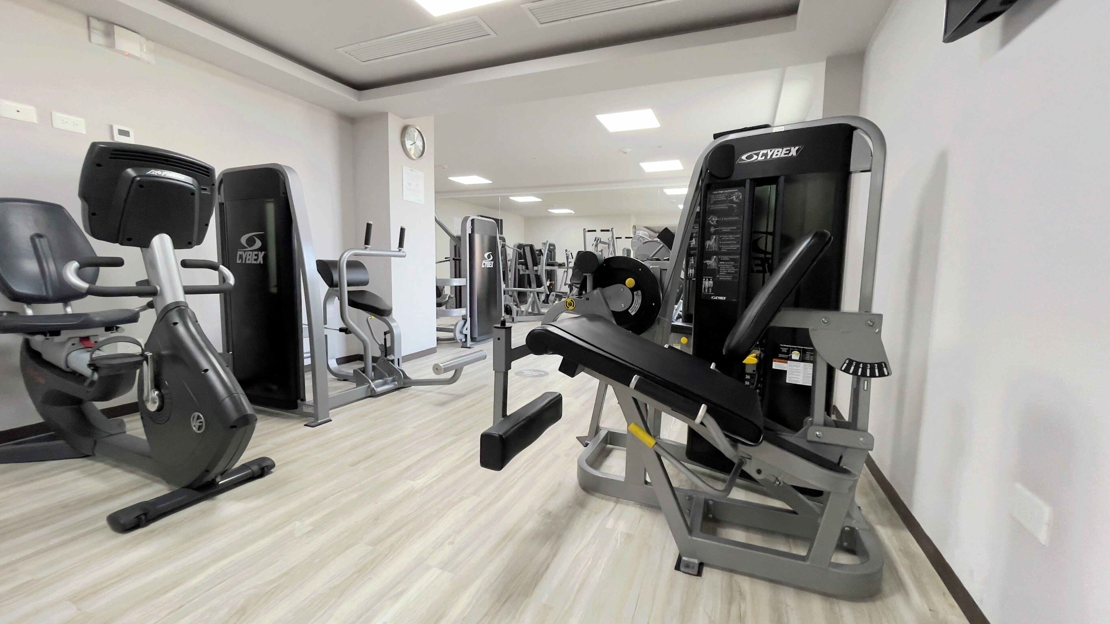 A gym with various exercise equipment including a treadmill, weight machines, and a bench press.