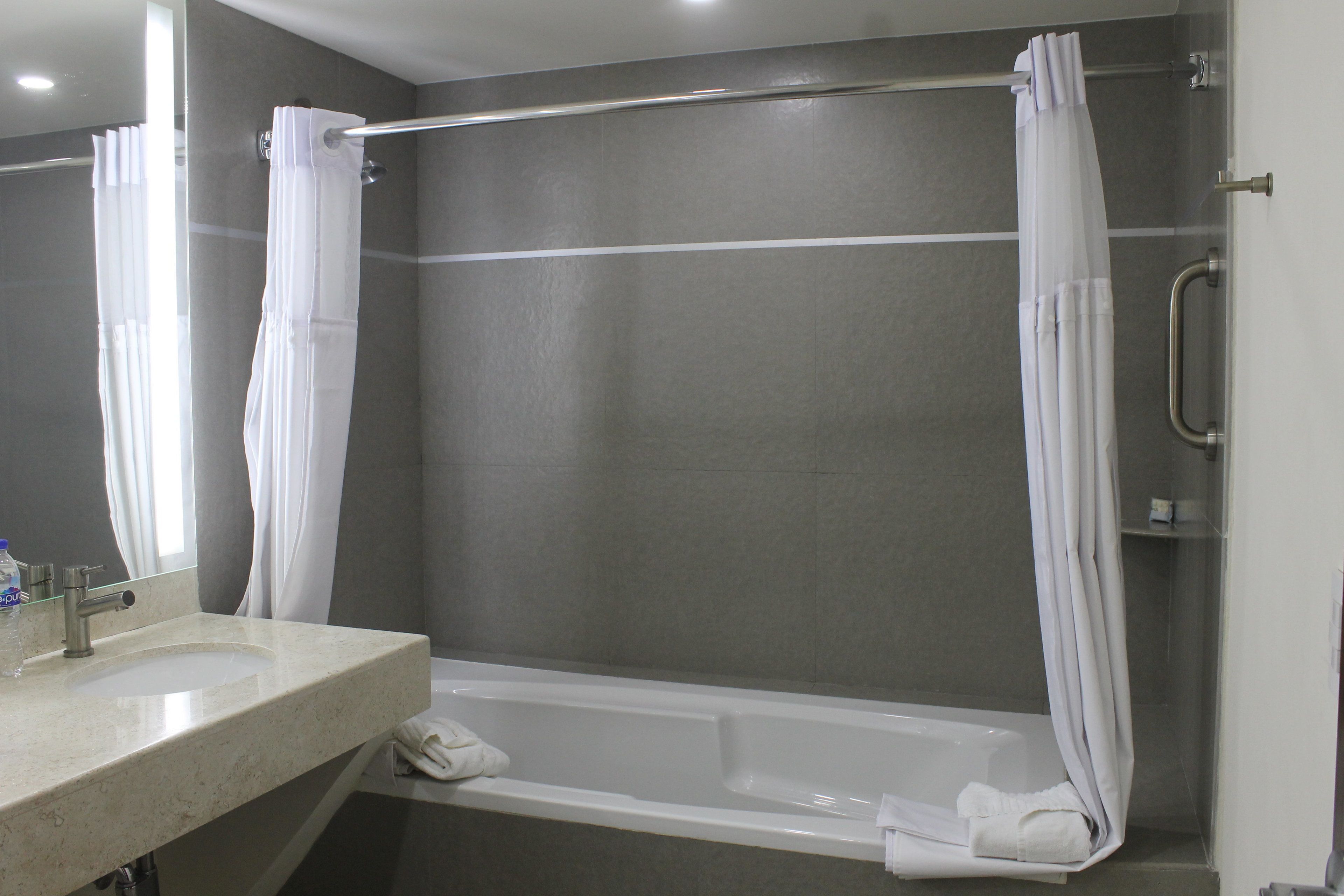 Un baño con bañera, lavamanos y cortina de ducha.
