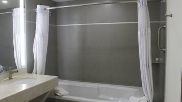 Un baño con bañera, lavamanos y cortina de ducha.