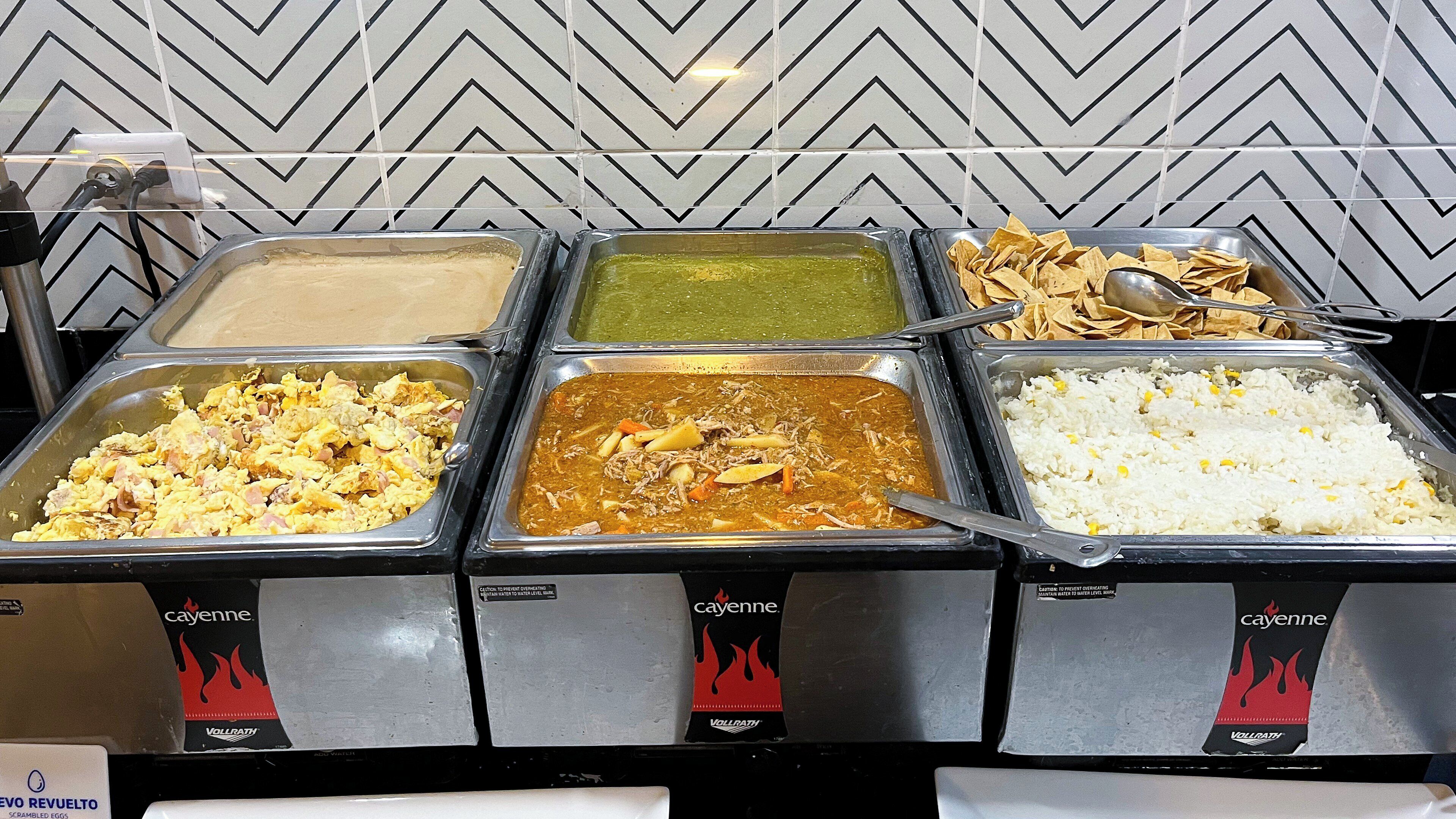 A buffet with various food options including scrambled eggs, curry, and rice.