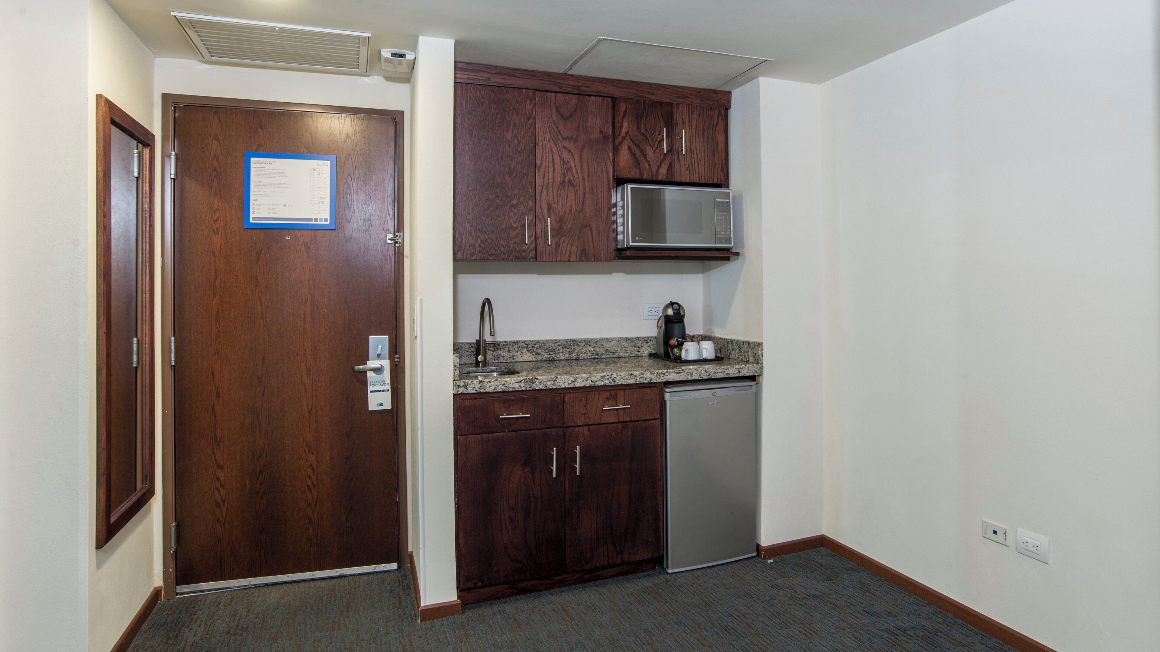 A compact kitchen with wooden cabinets, a built-in microwave, and a dishwasher.