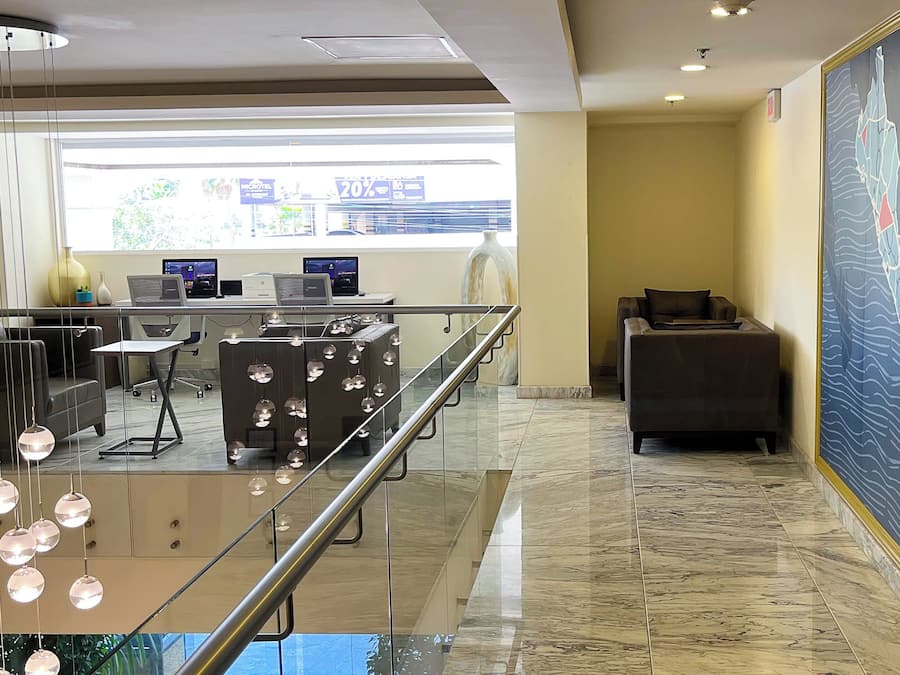 A modern lobby with a glass railing, a reception desk, computers, and a large abstract painting on the wall.