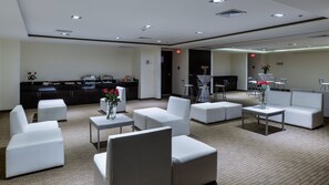 A hotel lobby with seating areas, a kitchenette, and a bar.