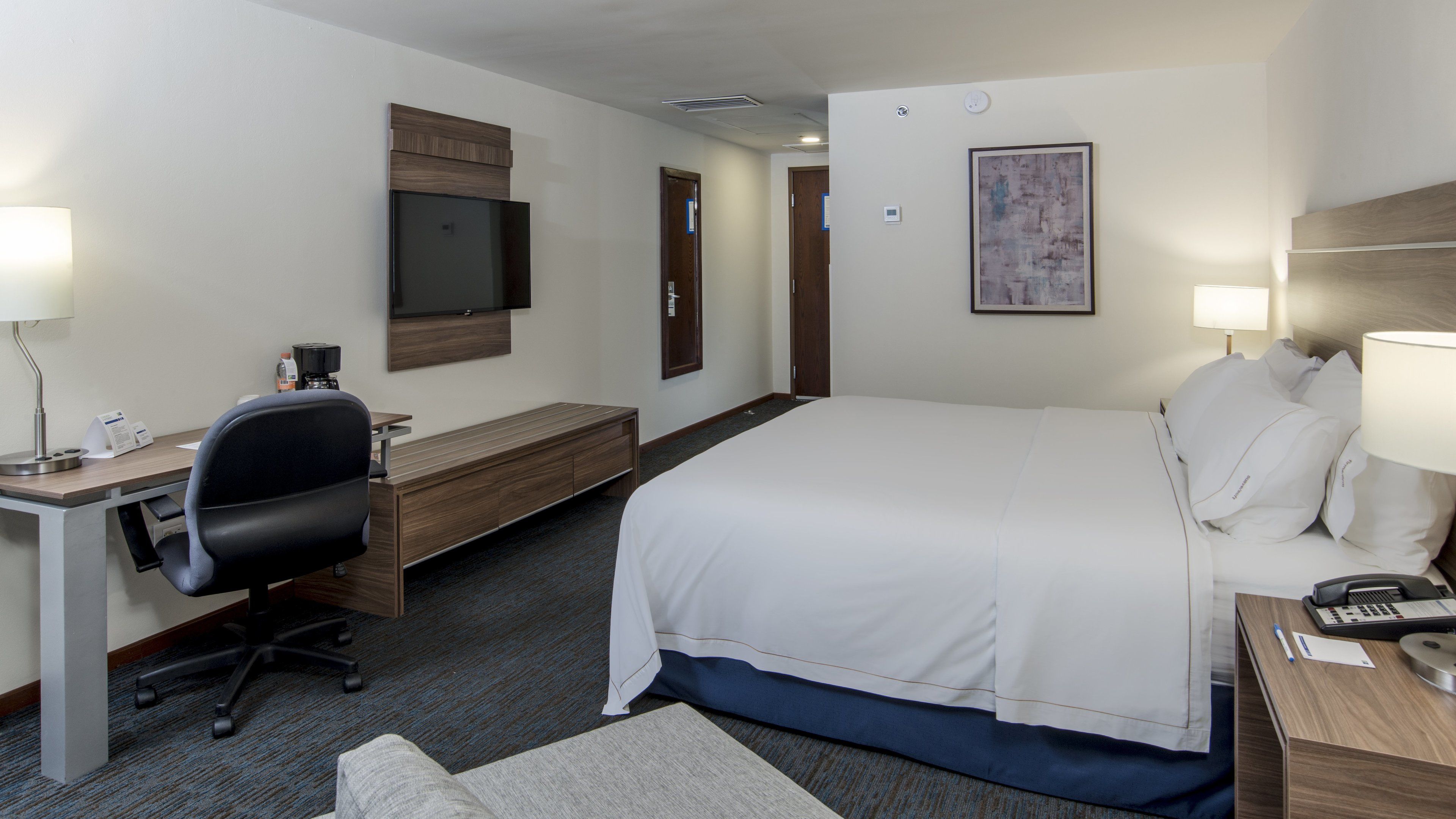 Una habitación de hotel con cama, escritorio, silla y televisión.