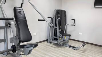 A gym with exercise equipment, including a bench and a weight machine.