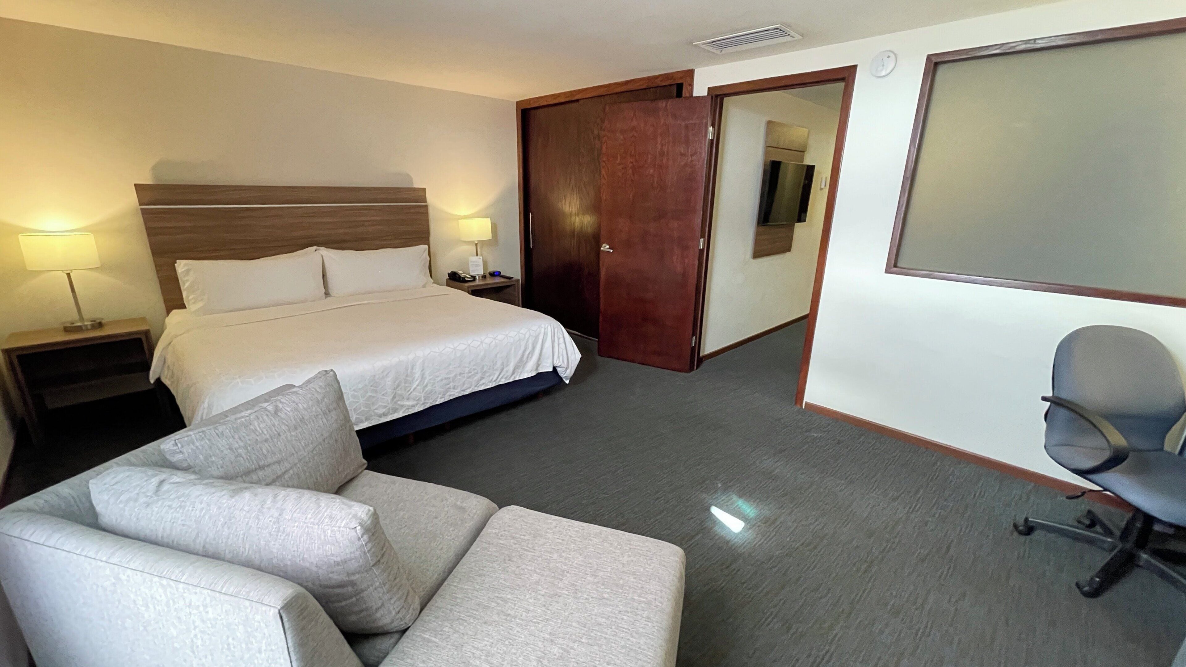 A hotel room with a bed, a sofa, a desk, and a chair.