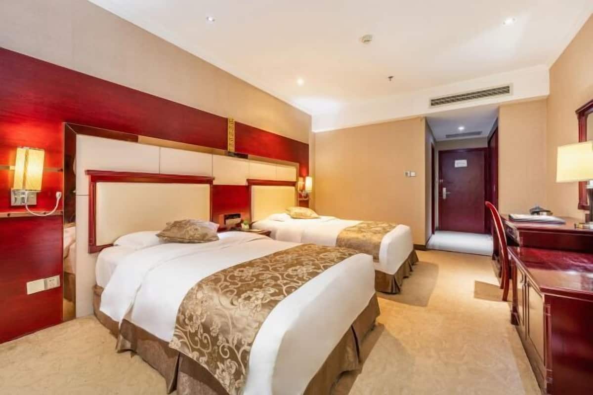 Quarto de hotel com duas camas, uma escrivaninha e uma cadeira.