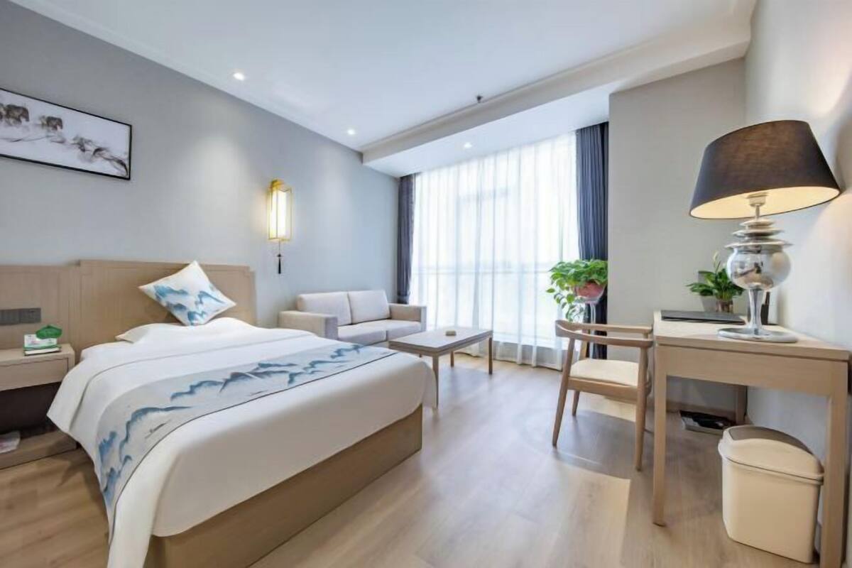 Quarto de hotel moderno com cama, sofá, escrivaninha e cadeira.