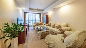 A modern living room with a sofa set, a coffee table, and a potted plant. - Guangming Hotel (Weinan)