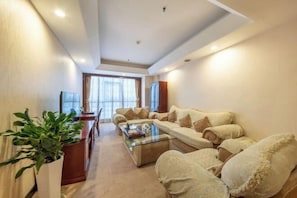 A modern living room with a sofa set, a coffee table, and a potted plant. - Guangming Hotel (Weinan)