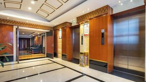 A hotel lobby with a marble floor, wooden paneling, and a reception area with seating. - Guangming Hotel (Weinan)