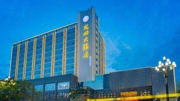 A modern hotel with a prominent vertical sign, multiple floors, and a glass facade.