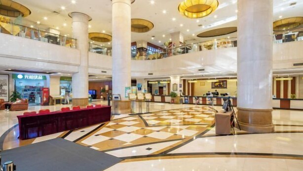A spacious lobby with a checkered floor, multiple levels, and a central reception area. - Guangming Hotel (Weinan)
