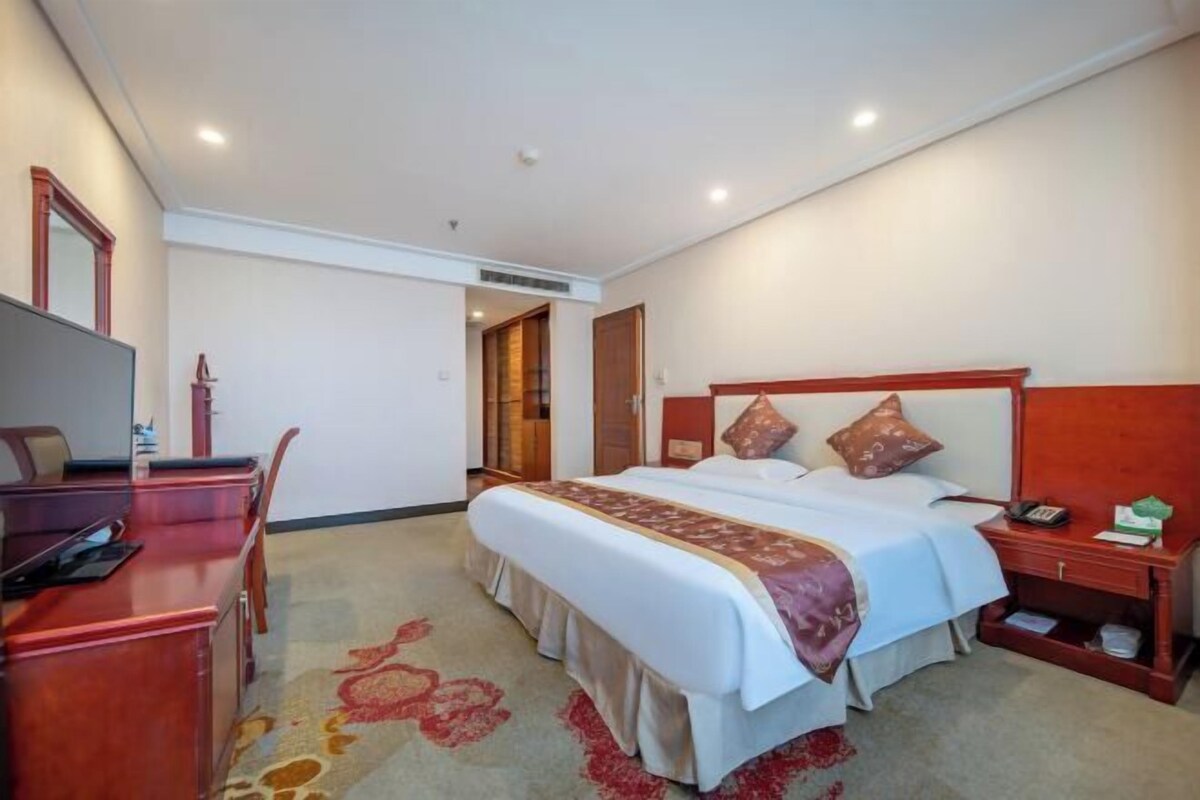 Une chambre d’hôtel avec un lit, un bureau et une table de chevet.
