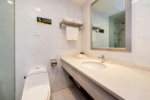 Une salle de bain moderne avec des toilettes, un lavabo et un miroir. On y trouve un porte-serviettes et un panneau sur le mur.