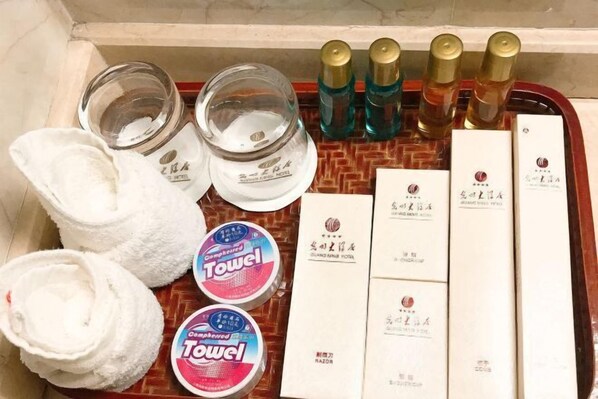 Un plateau contenant des articles de toilette, notamment des serviettes, un flacon de lotion et une boîte de mouchoirs.