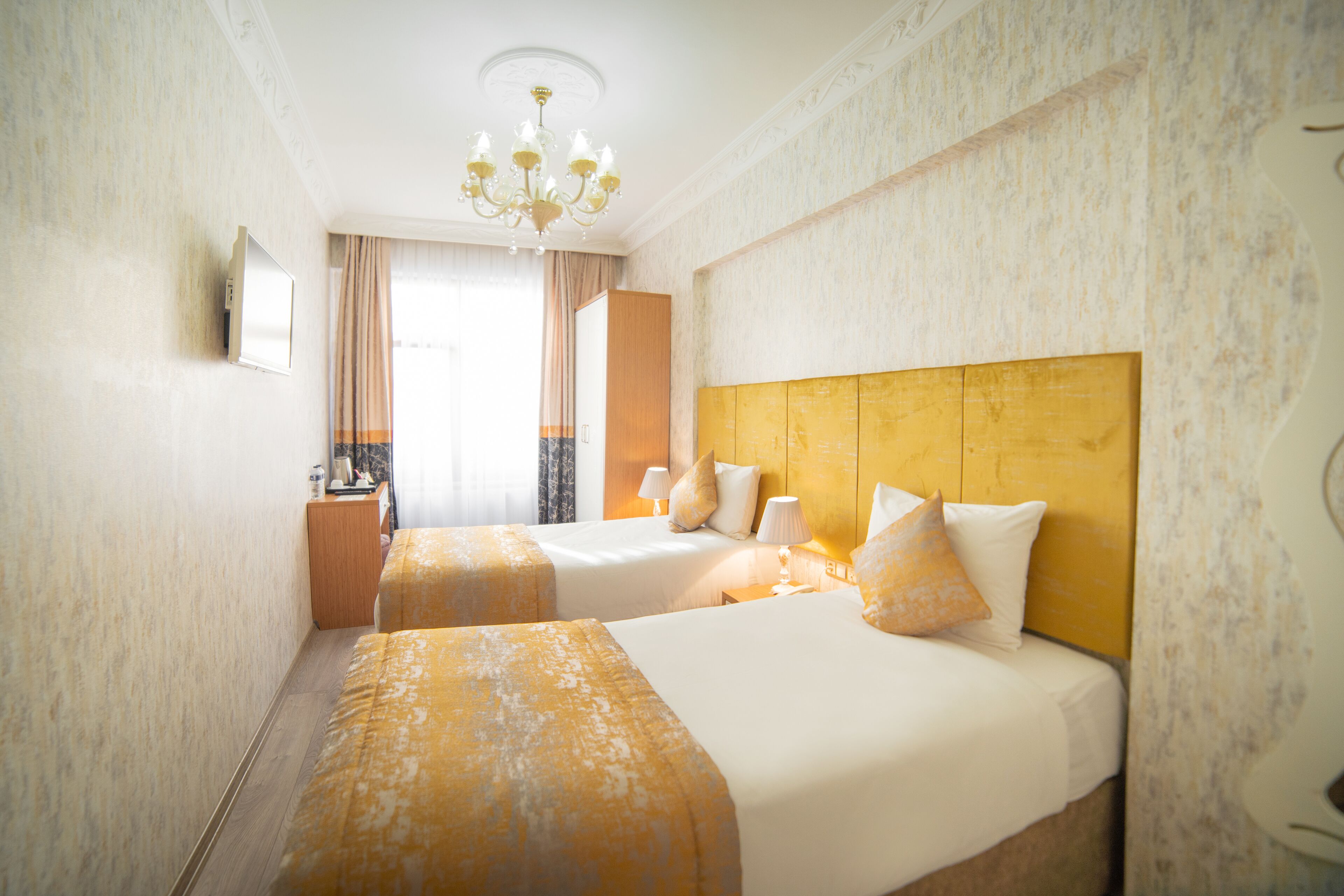 A hotel room with two beds, a chandelier, and a mirror on the wall.