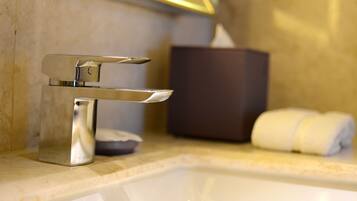 Un lavandino da bagno con un rubinetto moderno, una scatola di fazzoletti e un asciugamano sul ripiano.