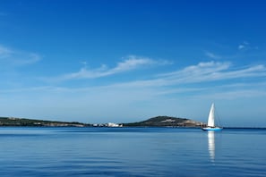 A calm sea with a sailboat, distant hills, and a clear sky. - Hotel Mercure Rif Nador (Nador)