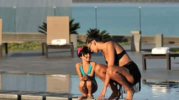 Una piscina techada, una piscina al aire libre, sombrillas