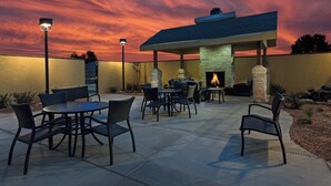 An outdoor patio area with a stone fireplace, seating, and a view of the sky.
