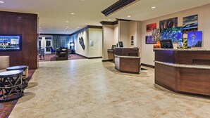 A hotel lobby with a reception desk, seating area, and artwork on the walls.
