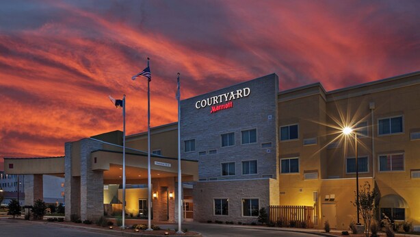 A Courtyard Marriott hotel with a stone facade, multiple windows, and a flagpole.