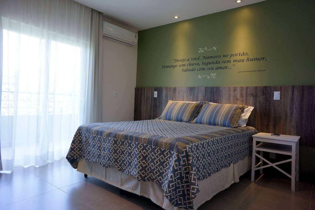 Un dormitorio con una cama grande, una mesita de noche y una pared con una cita.