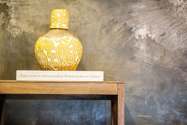 A decorative vase with intricate patterns on a wooden shelf against a textured wall.