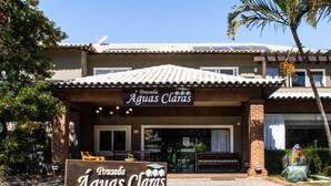 A building with a sign reading "Pousada Águas Claras" and a patio area with outdoor seating.