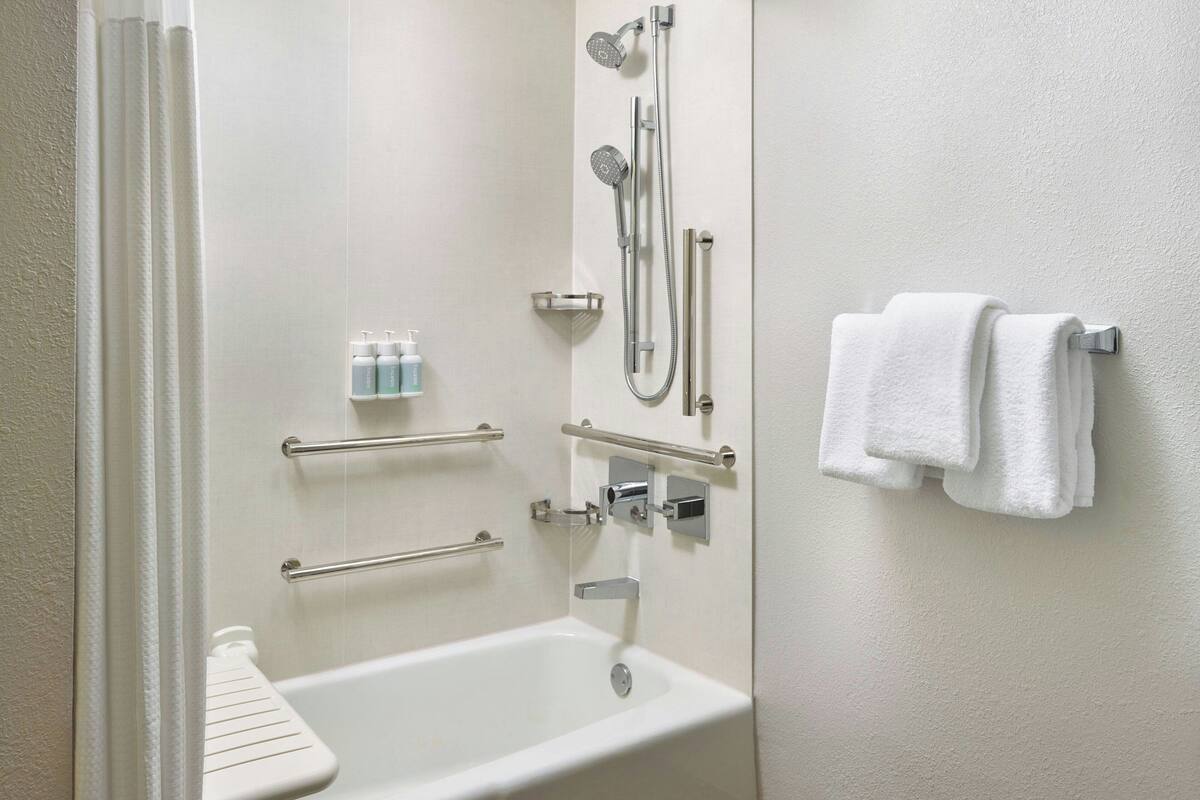 A modern bathroom with a bathtub, shower, and towel rack.