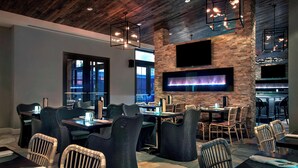 A restaurant with wicker chairs, a stone floor, a brick wall, and a flat-screen TV mounted above a fireplace. - Courtyard by Marriott Philadelphia Lansdale (Harleysville)