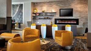 A modern hotel lobby with a fireplace, leather armchairs, a flat-screen TV, and a patterned carpet. - Courtyard by Marriott Philadelphia Lansdale (Harleysville)