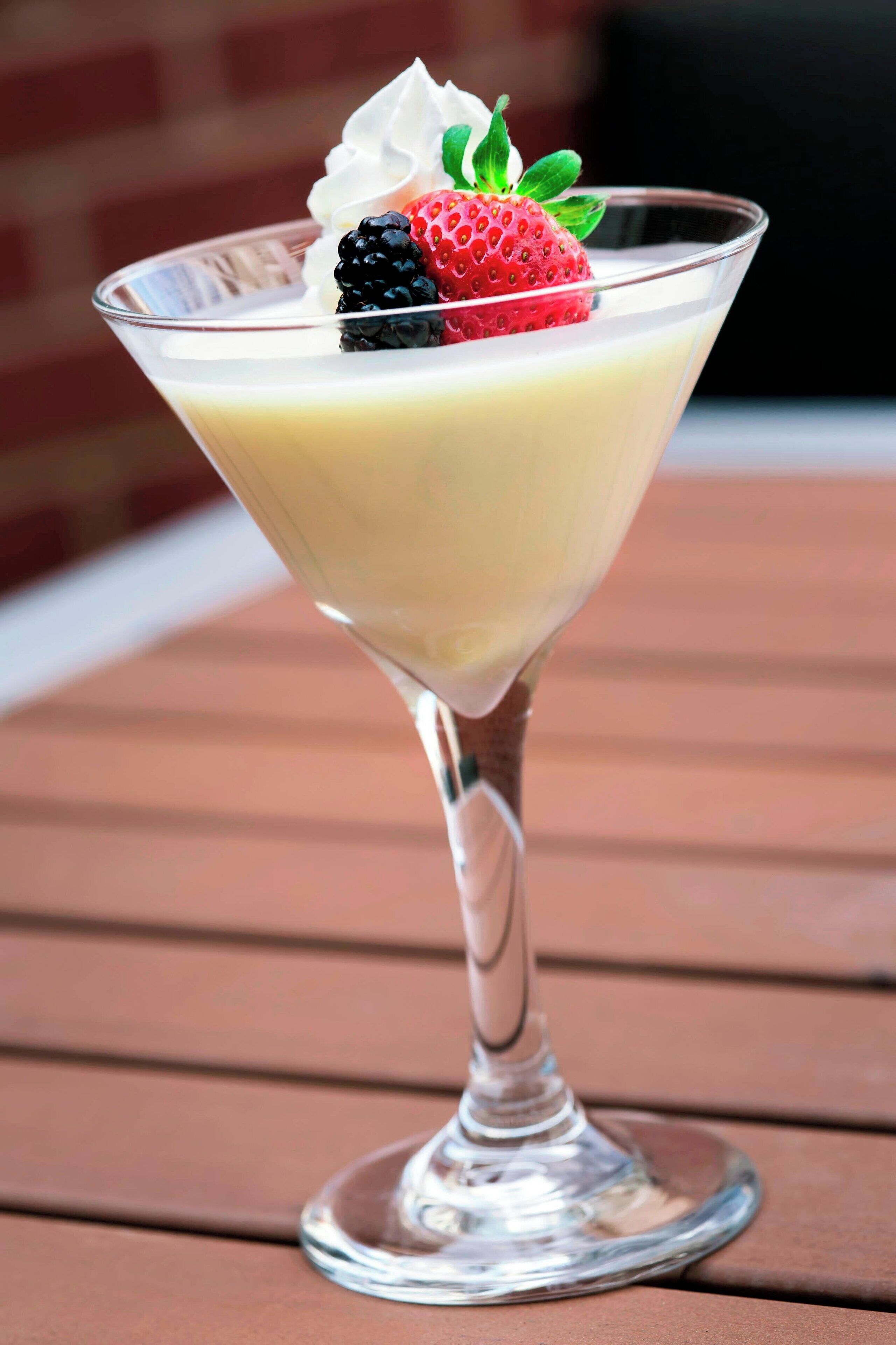 A dessert in a martini glass on a wooden table.