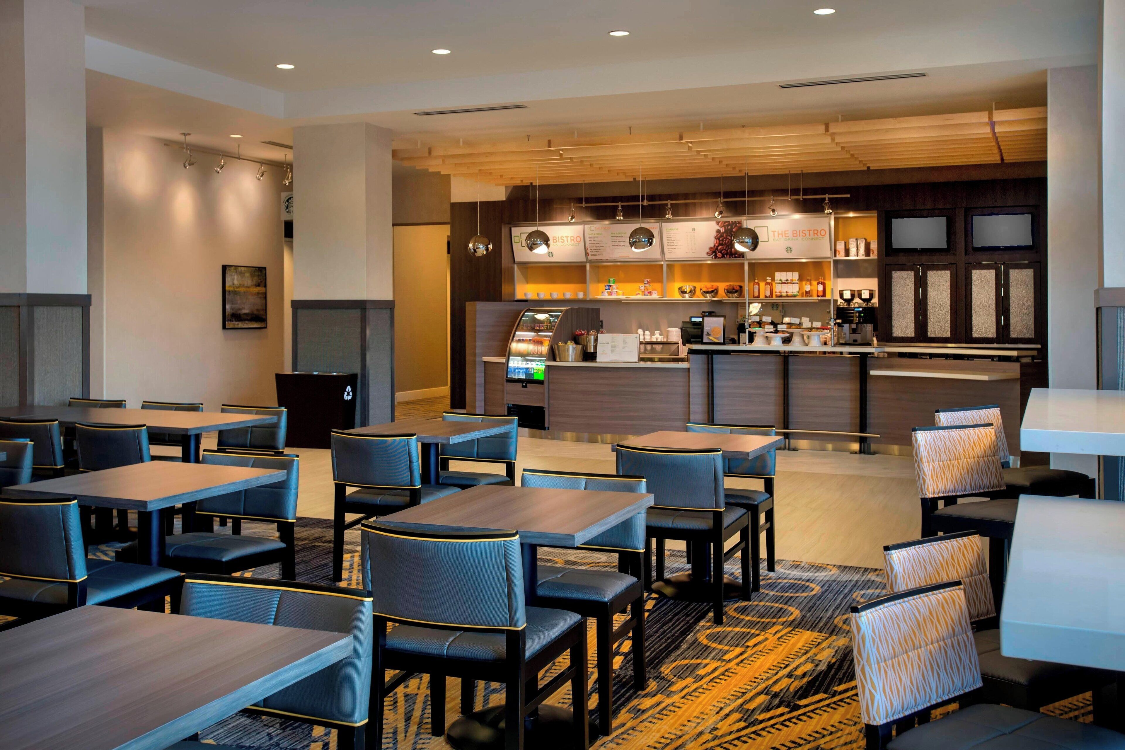 A modern bistro with a bar area, multiple seating options including tables and booths, and a patterned carpet.