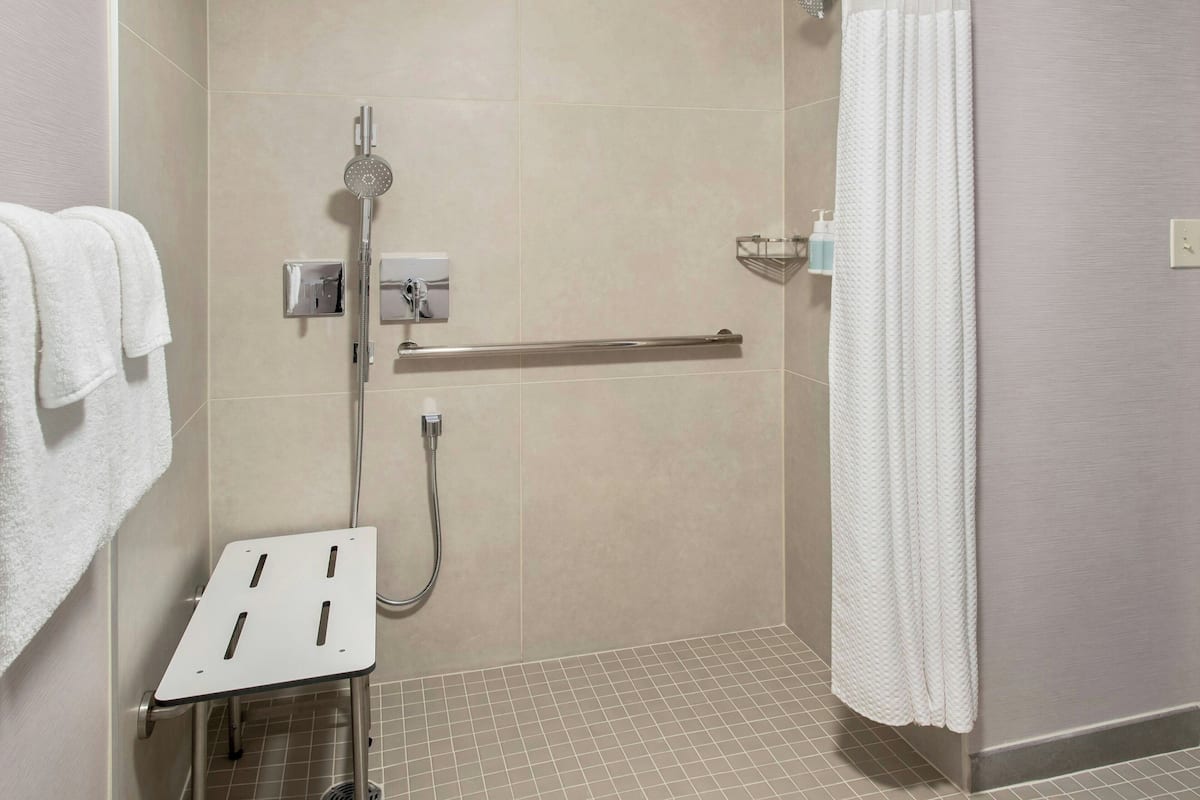 A shower area with a grab bar, a towel rack, and a showerhead.
