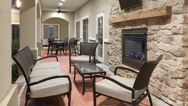 An outdoor patio area with stone walls, a fireplace, and seating arrangements. - TownePlace Suites by Marriott Seguin (Seguin)