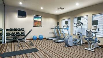 A gym with treadmills, elliptical machines, dumbbells, and exercise balls.