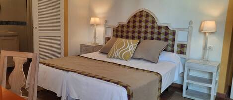 A neatly arranged bedroom with a bed, two bedside tables with lamps, a chair, and a wardrobe.