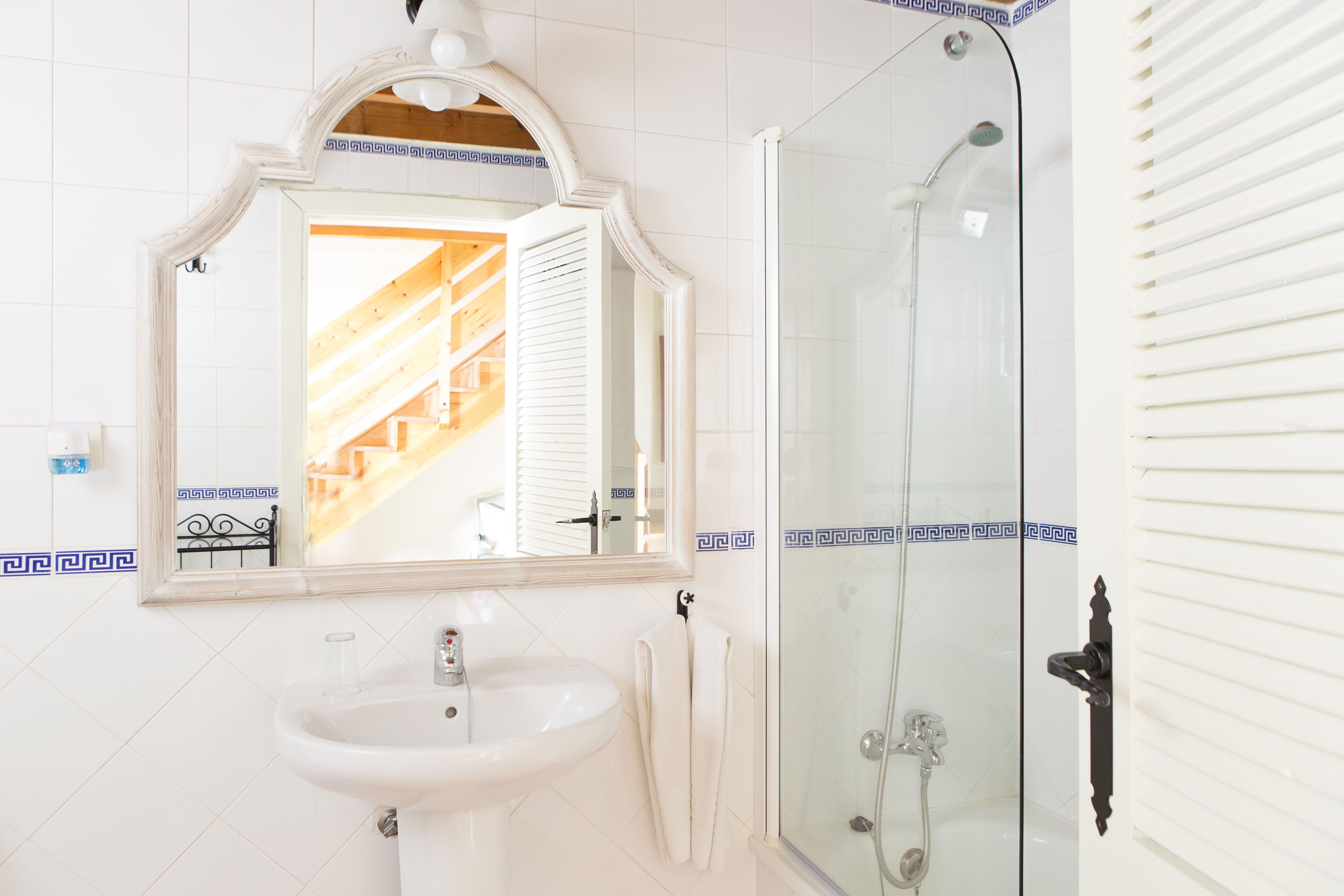 Une salle de bain avec un lavabo blanc, un miroir et une douche à parois de verre.