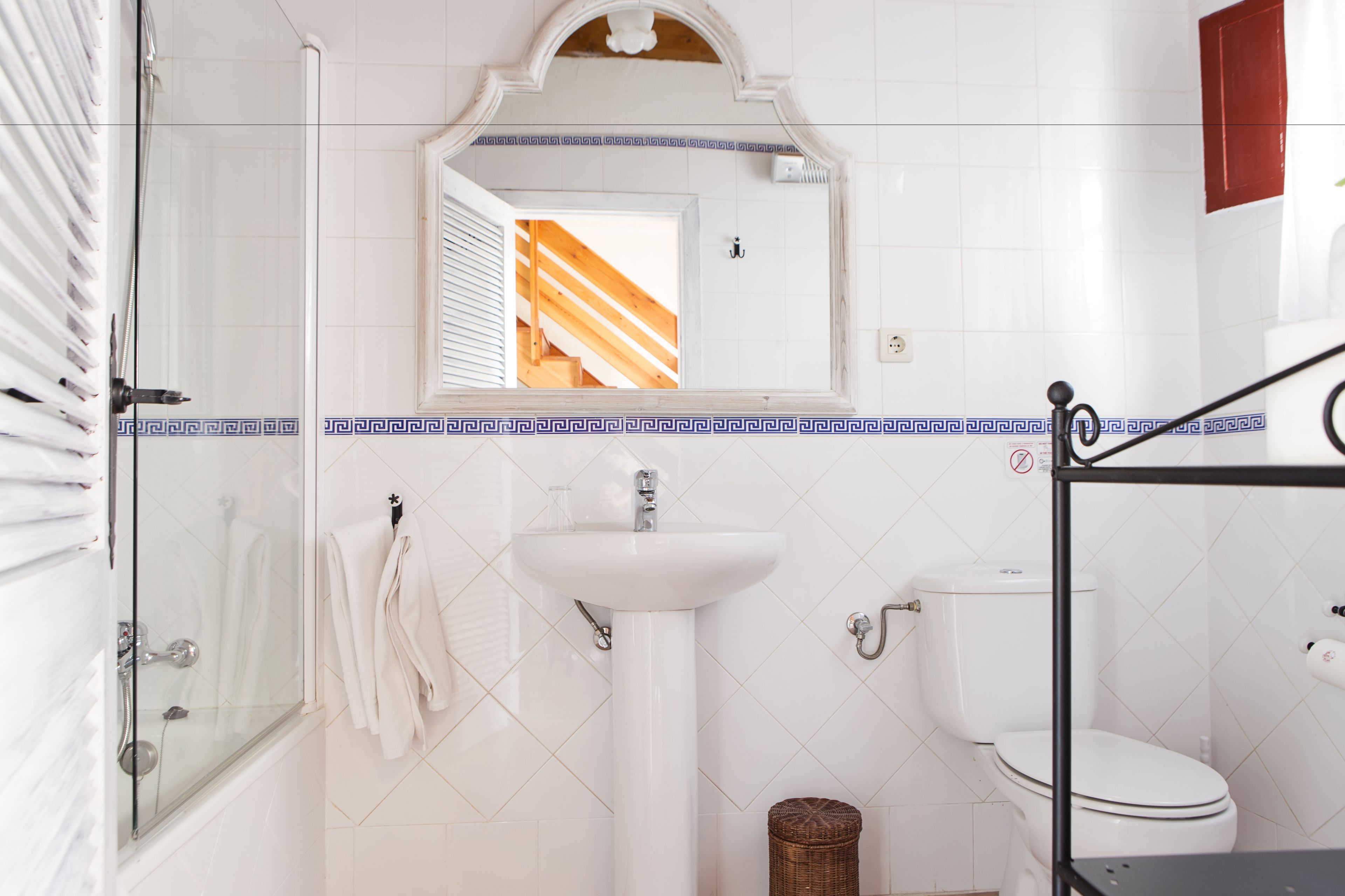 A bathroom with a glass shower enclosure, a white sink, and a toilet.