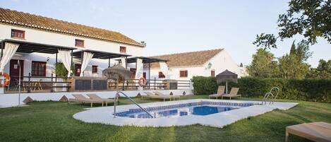 Una piscina al aire libre, sombrillas, sillones reclinables de piscina