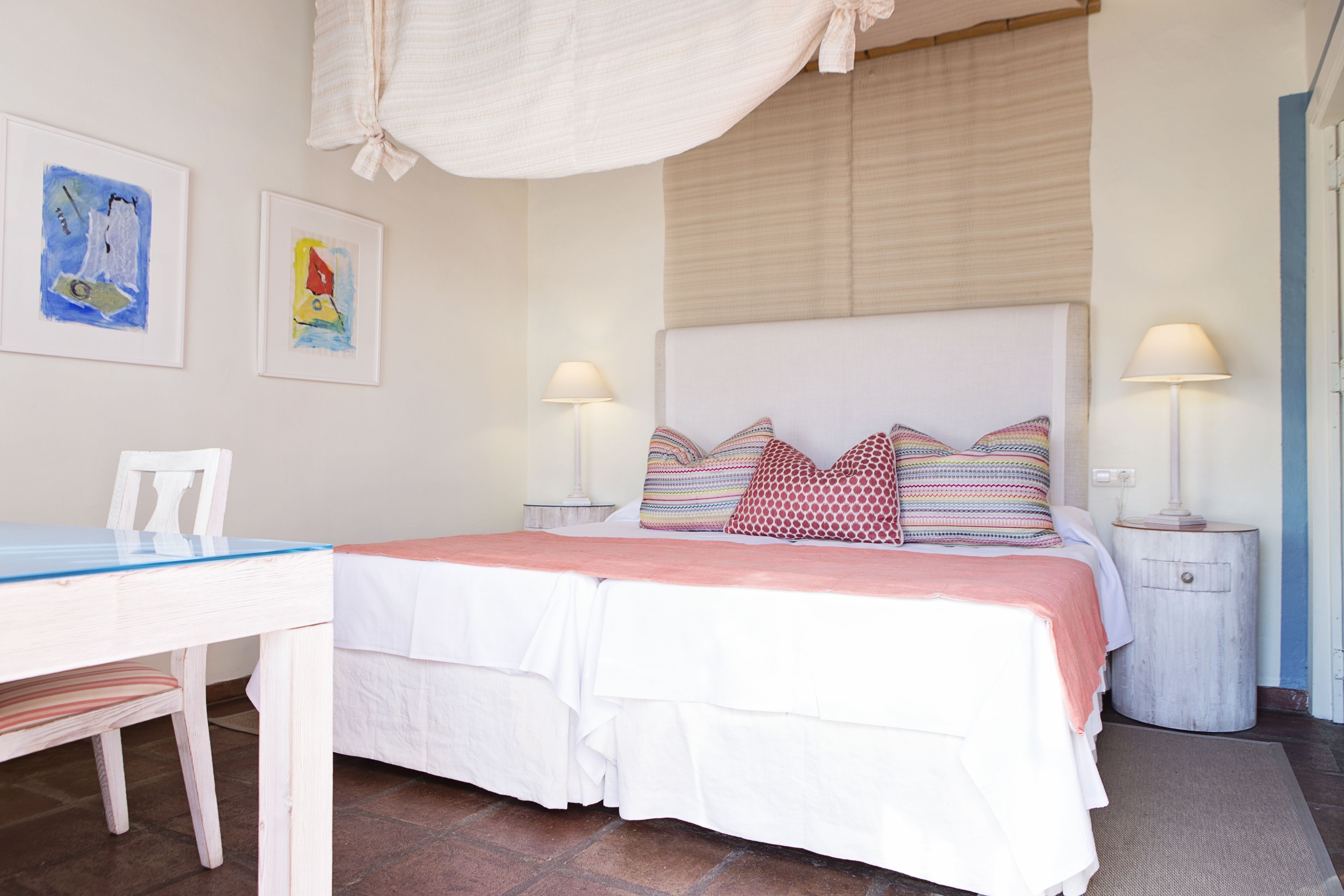 A bedroom with a bed, two bedside tables, a nightstand, a chair, and a desk.