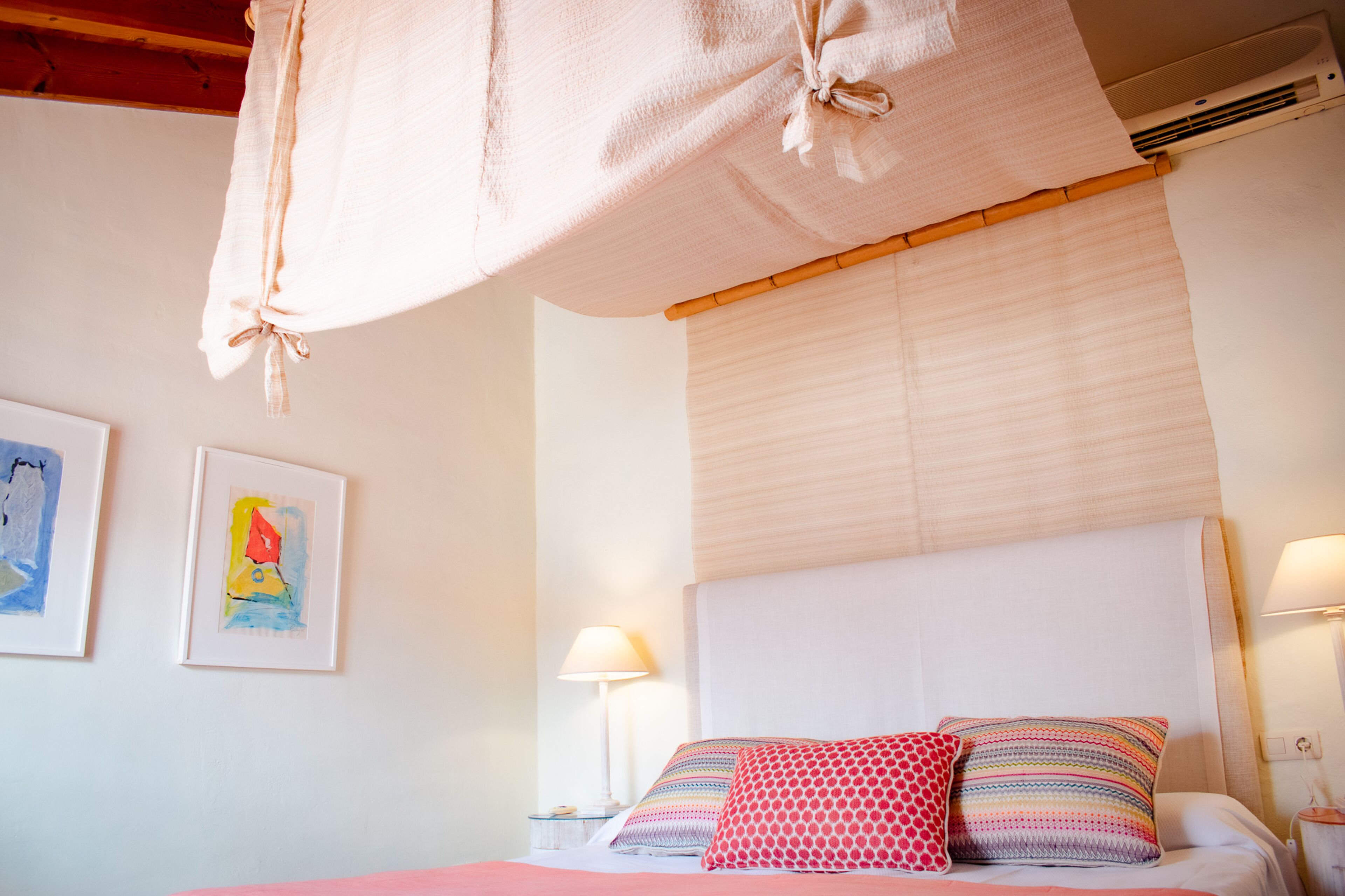 Un dormitorio con cama, almohadas, una lámpara de noche y decoración en la pared.
