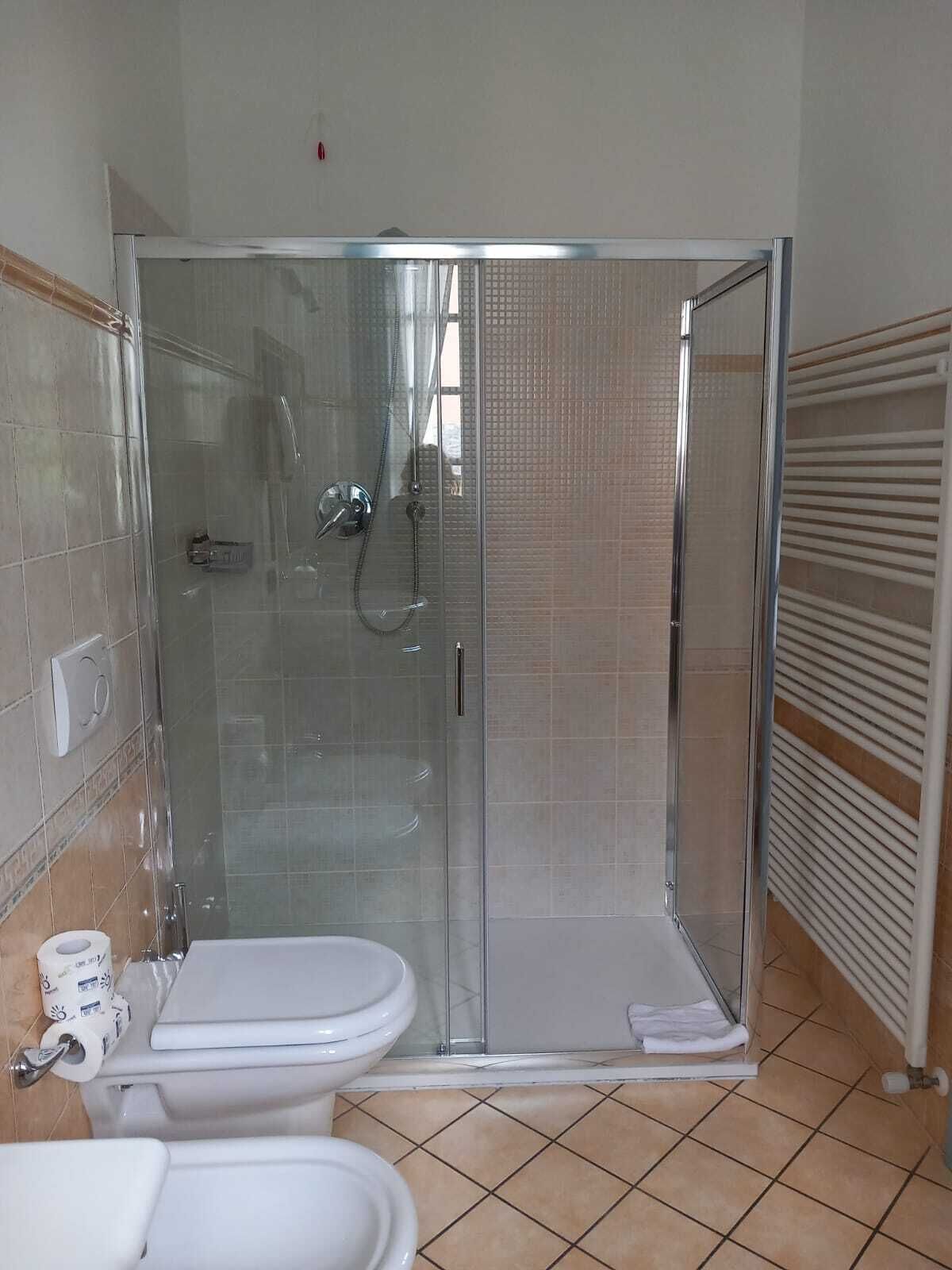 A bathroom with a glass-enclosed shower, a toilet, and a sink.