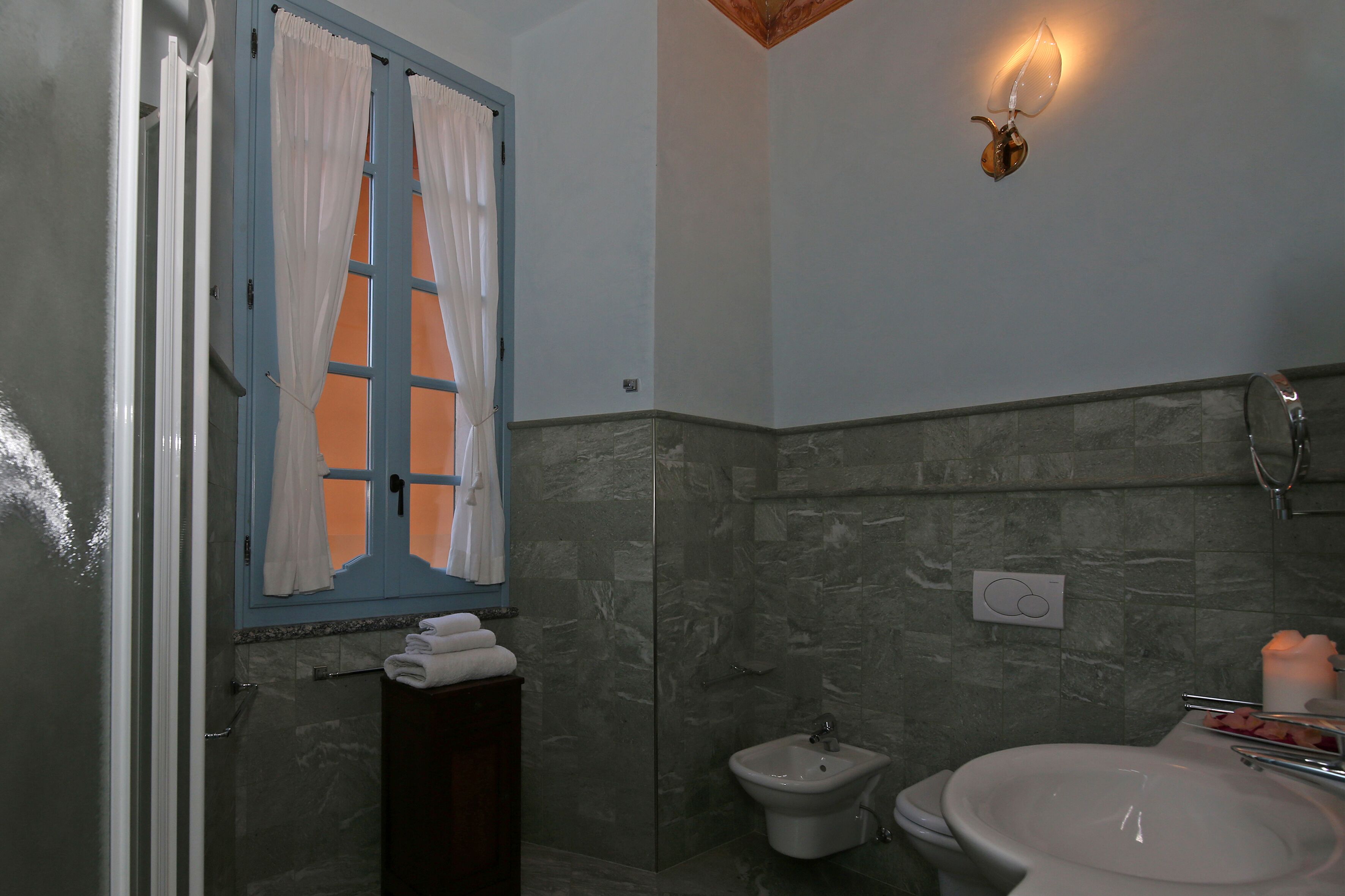 A bathroom with a shower, a bidet, a sink, and a towel rack.