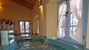 A spa area with a hot tub, wooden ceiling, and a view of the outside through a door with curtains. - Palazzo del Vicerè  (Lezzeno)