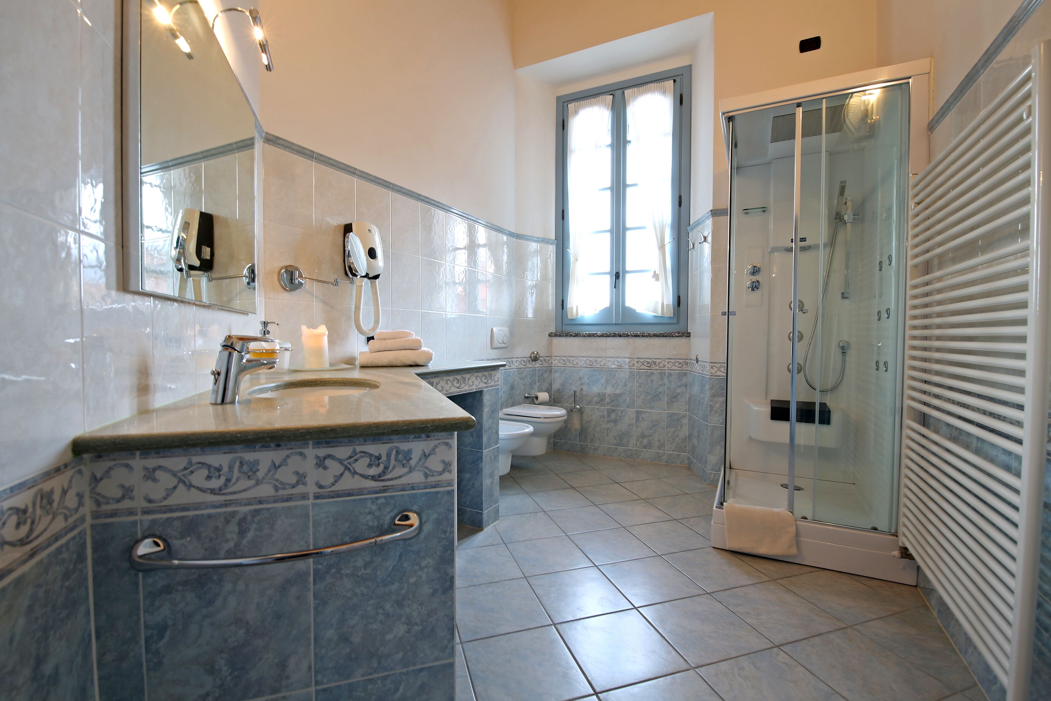 Une salle de bain avec une douche à parois de verre, un lavabo avec un porte-serviettes et des toilettes.